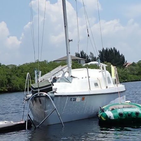 A moored sailboat listing heavily with its stern low in the water